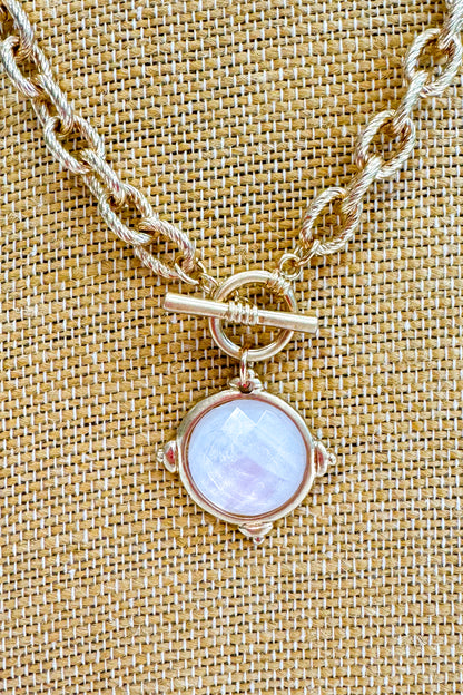 Necklace with a round pendant on a textured beige background