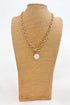 Gold chain necklace with a pendant on a brown mannequin bust against a white background