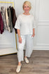 Front view of woman wearing Swagger Boutique’s Grey Round Neck Short Sleeve Top with matching barrel pants with clothes hanging in the background.