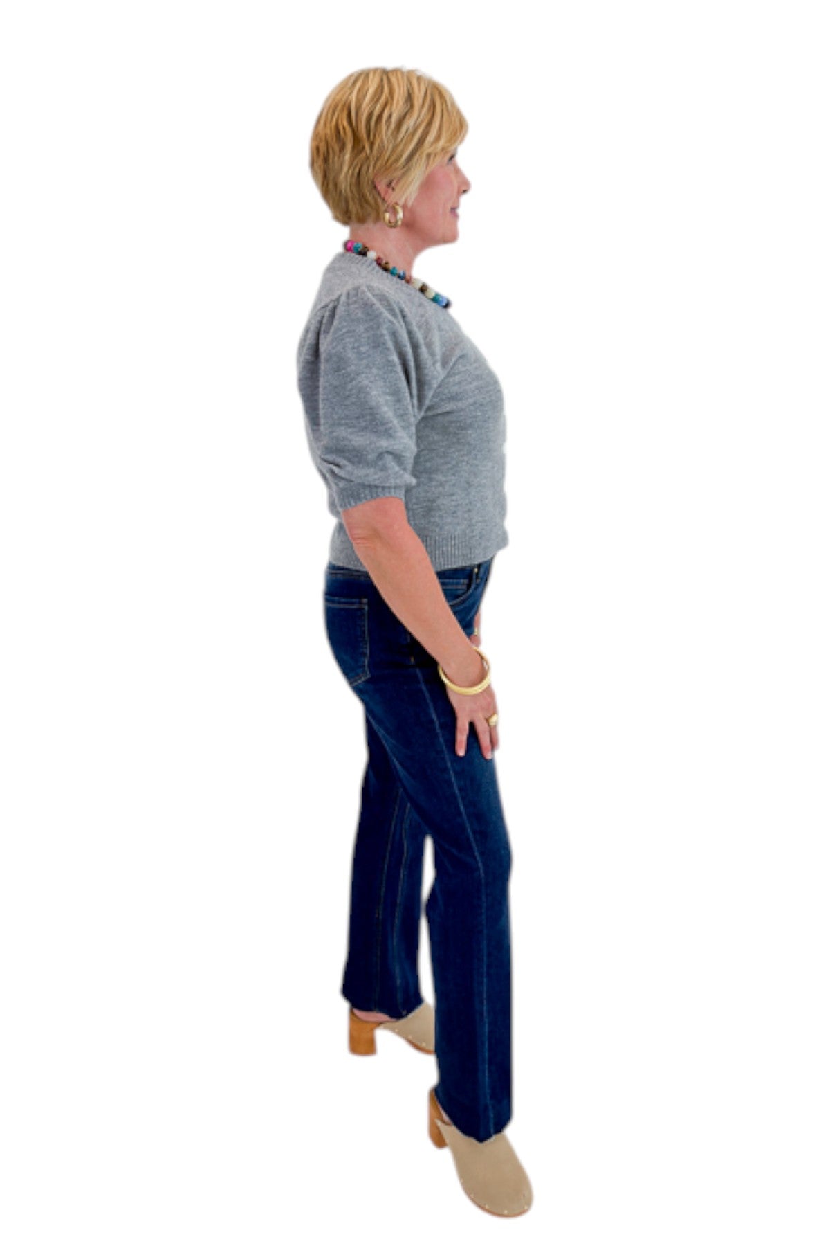 Side view of woman wearing Swagger Boutique’s Grey Button Up Short Sleeve Cardigan with jeans against white studio background.