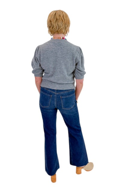 Back view of woman wearing Swagger Boutique’s Grey Button Up Short Sleeve Cardigan with jeans against white studio background.