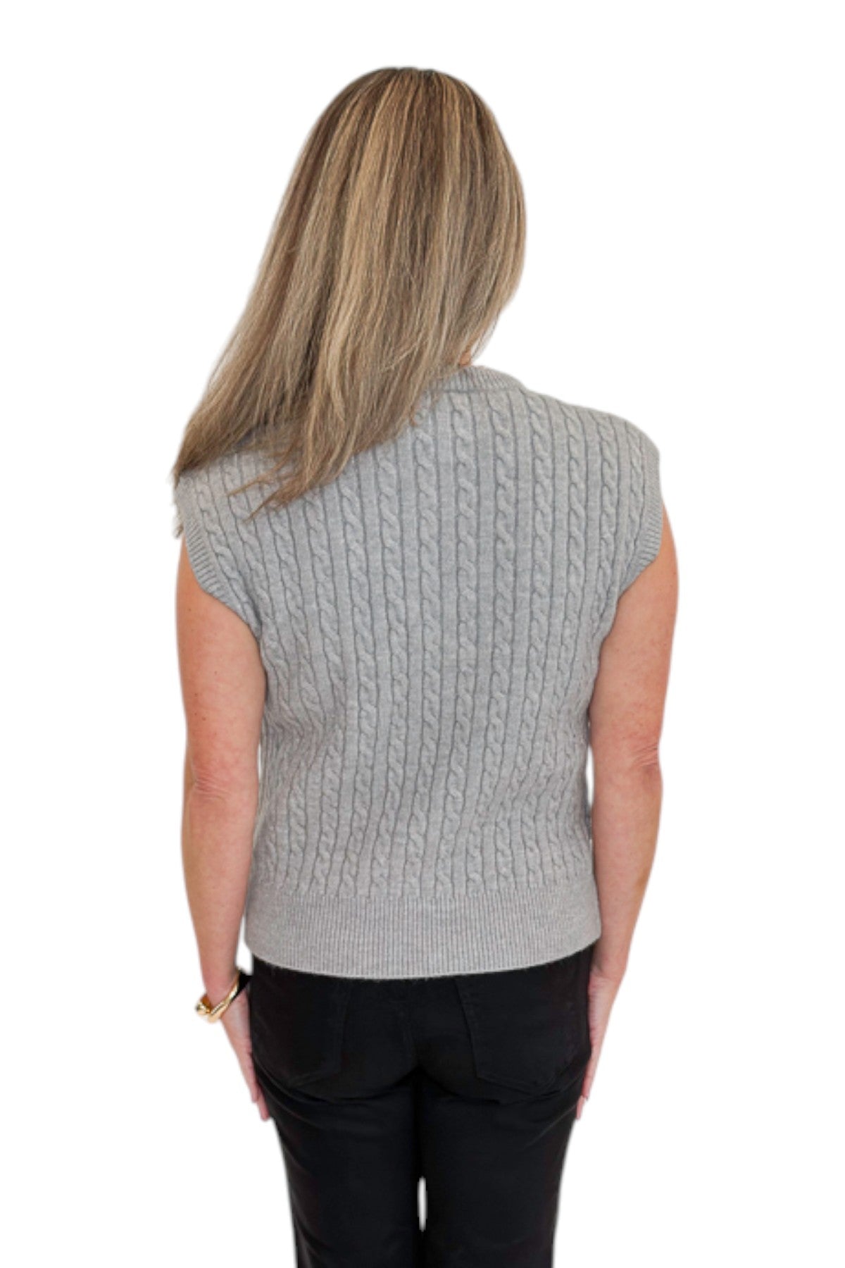 Back view of woman wearing Swagger Boutique’s Grey Cable Knit Denim Collared Sleeveless Sweater with jeans against white studio background.