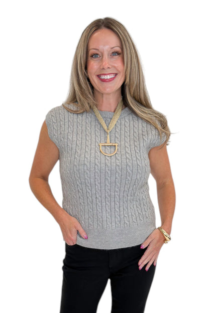 Front view of woman wearing Swagger Boutique’s Grey Cable Knit Denim Collared Sleeveless Sweater with jeans against white studio background.