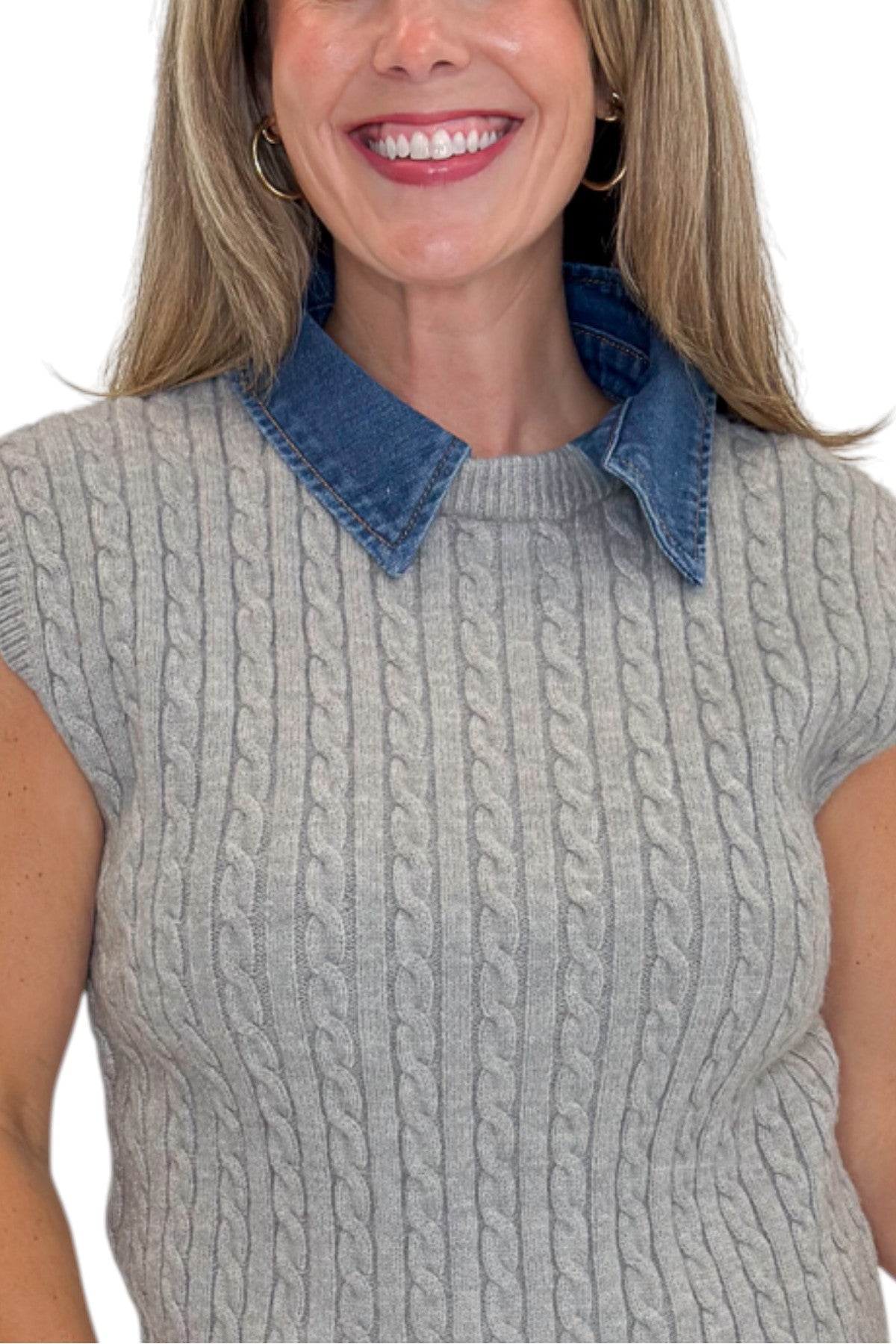 Front detail view of woman wearing Swagger Boutique’s Grey Cable Knit Denim Collared Sleeveless Sweater with jeans against white studio background.