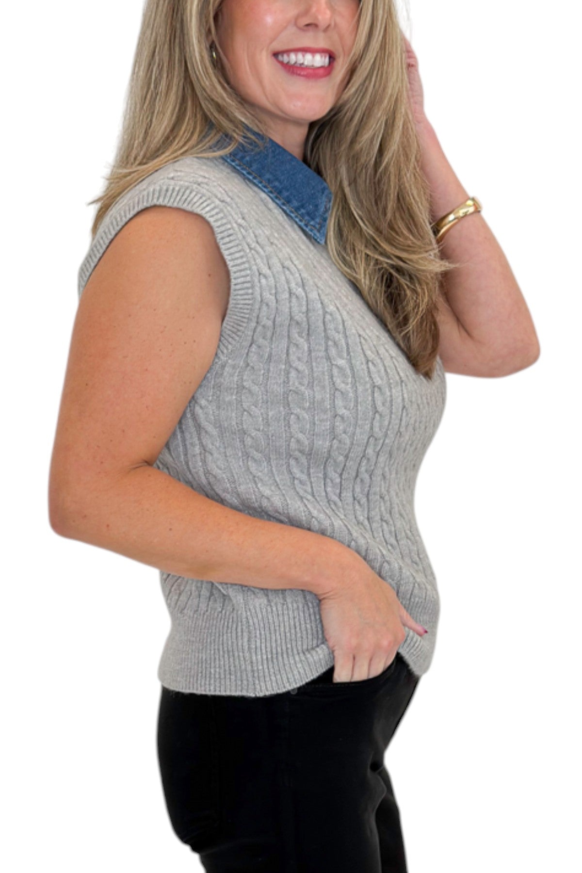 Side detail view of woman wearing Swagger Boutique’s Grey Cable Knit Denim Collared Sleeveless Sweater with jeans against white studio background.