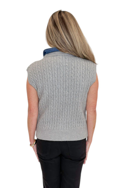 Back view of woman wearing Swagger Boutique’s Grey Cable Knit Denim Collared Sleeveless Sweater with jeans against white studio background.