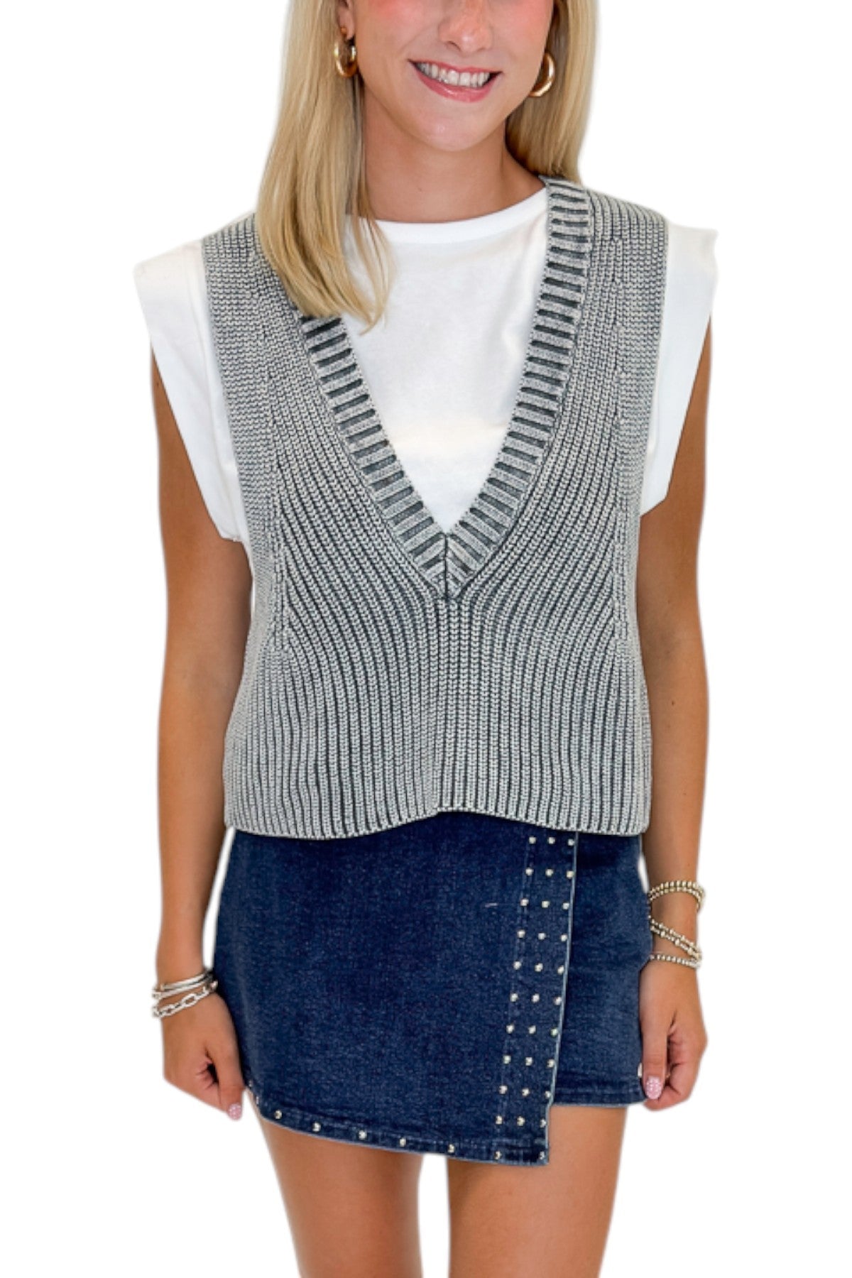 Front detail view of woman wearing Swagger Boutique’s Grey Layered Sweater Top with Dark Wash Studded Denim Skort against white studio background.