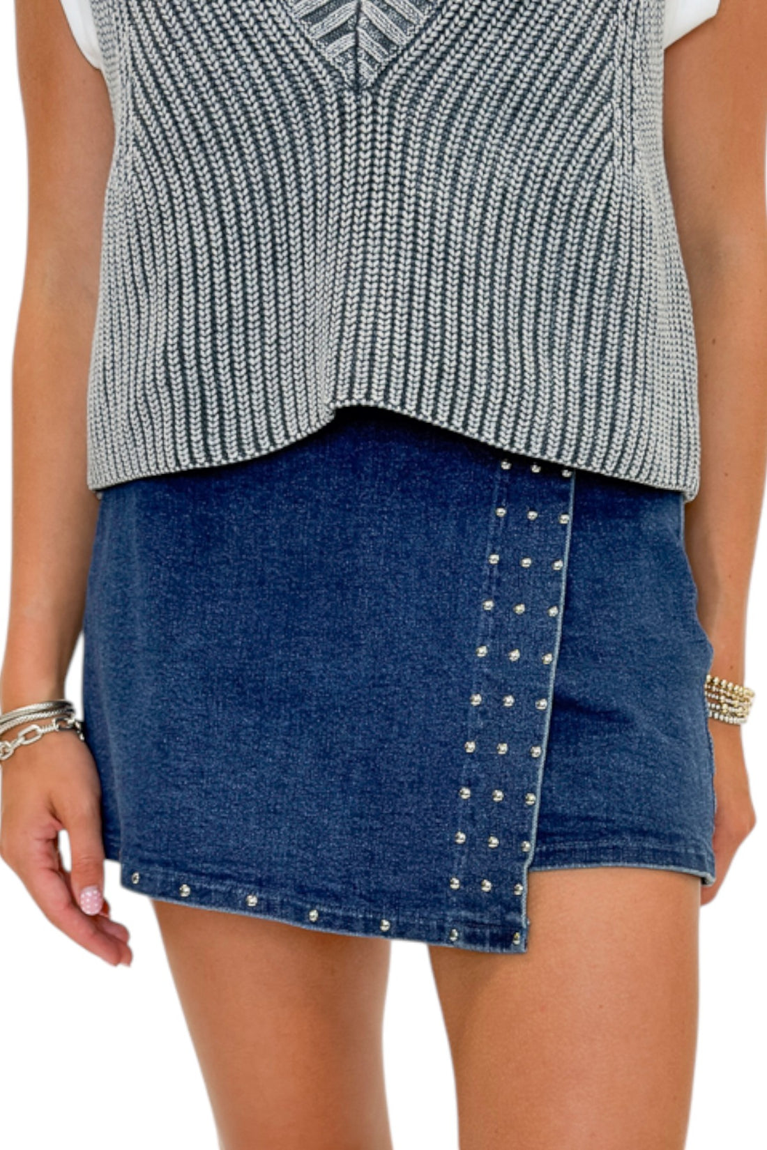 Front detail view of woman wearing Swagger Boutique’s Grey Layered Sweater Top with Dark Wash Studded Denim Skort against white studio background.