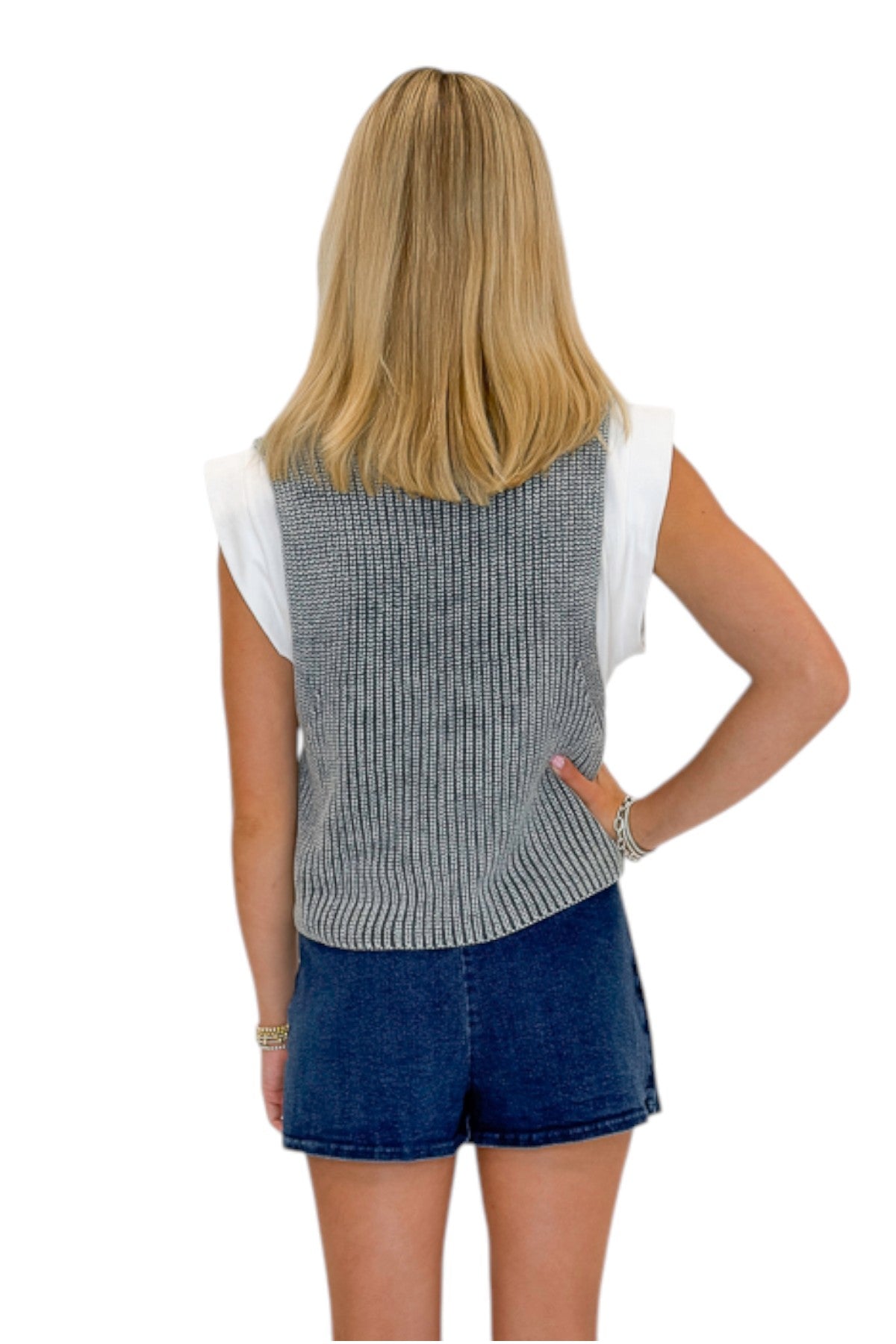Back view of woman wearing Swagger Boutique’s Grey Layered Sweater Top with Dark Wash Studded Denim Skort against white studio background.