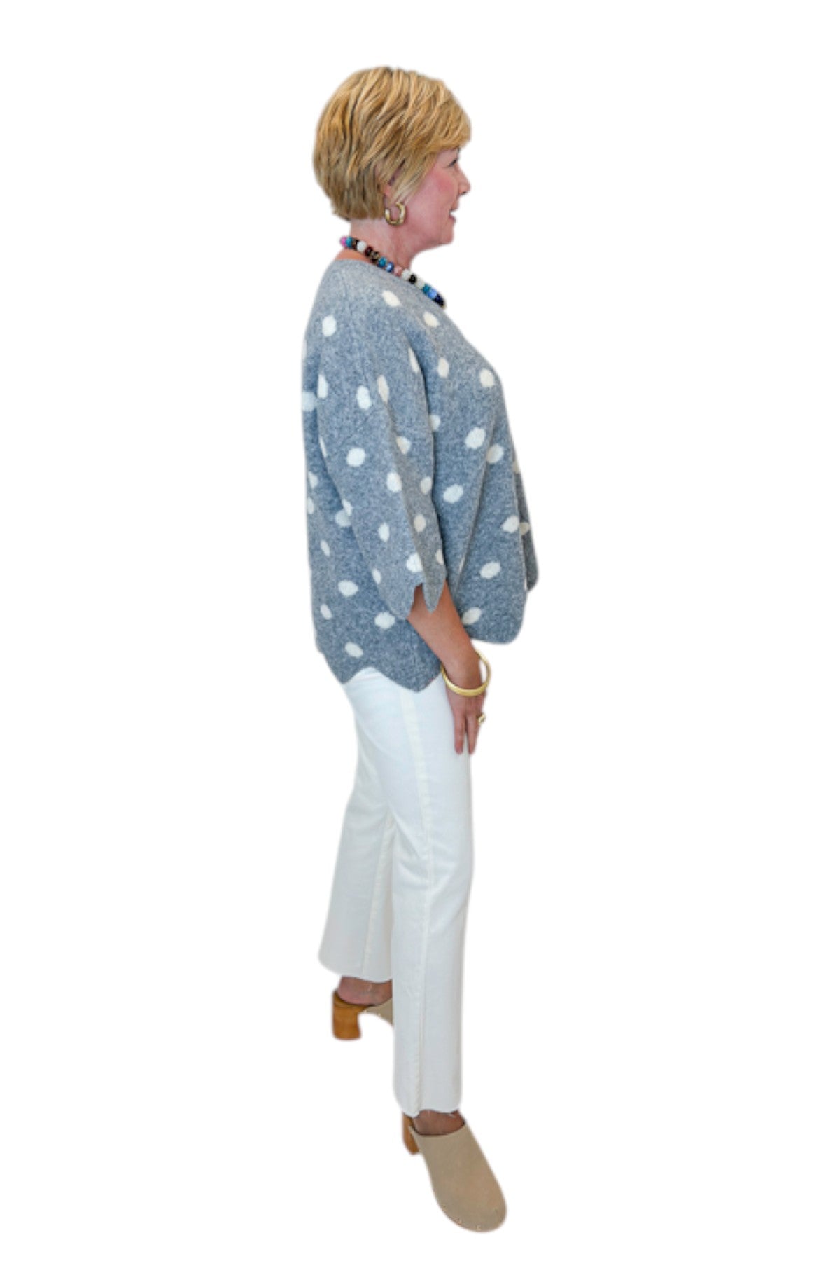 Side view of woman wearing Swagger Boutique’s Grey Polka Dot Short Sleeve Sweater by Entro with jeans against white studio background.