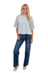 Front view of woman wearing Swagger Boutique’s Grey Ribbed Short Sleeve Sweater with jeans against white studio background.