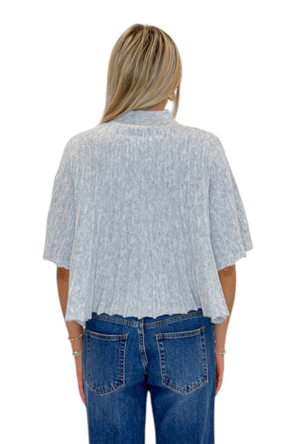 Back view of woman wearing Swagger Boutique’s Grey Ribbed Short Sleeve Sweater with jeans against white studio background.