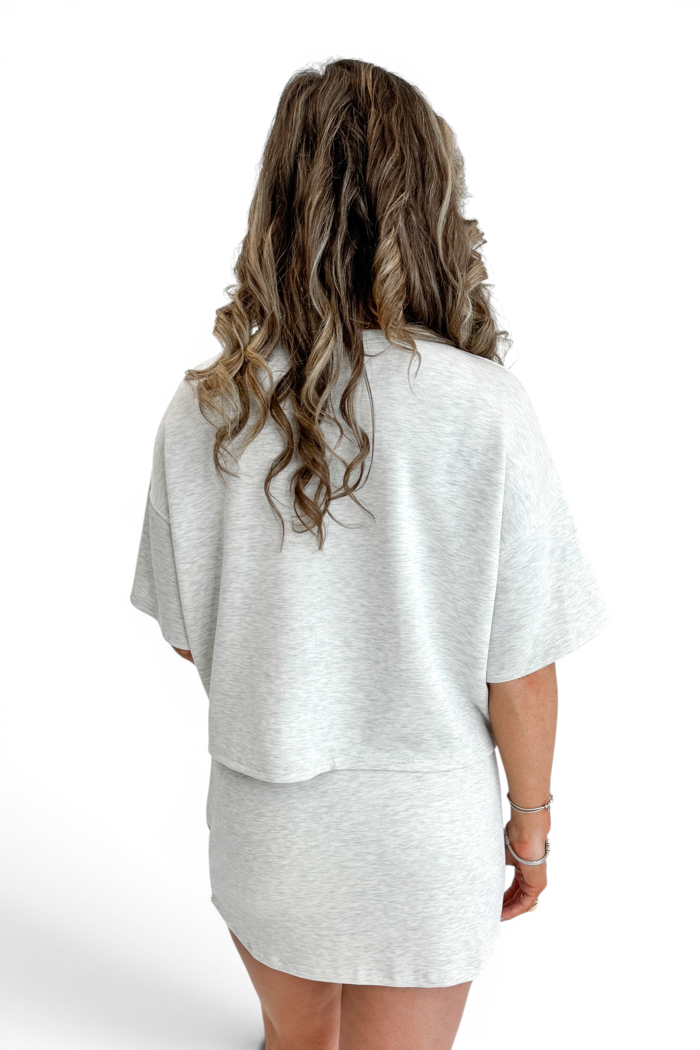 Back view of woman wearing Swagger Boutique’s Grey Round Neck Short Sleeve Top with matching Grey Skort against white studio background.