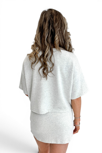 Back view of woman wearing Swagger Boutique’s Grey Round Neck Short Sleeve Top with matching Grey Skort against white studio background.