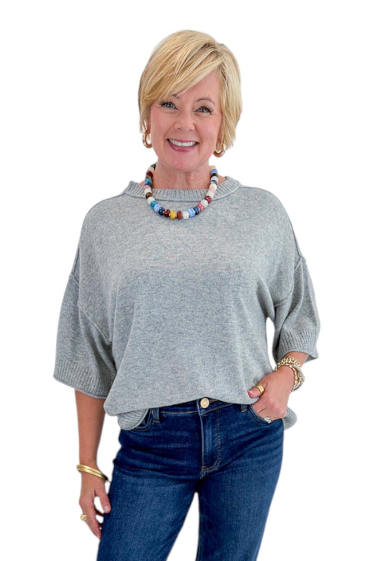 Front view of woman wearing Swagger Boutique’s Grey Short Sleeve Sweater with jeans against white studio background.