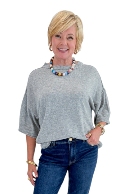 Front view of woman wearing Swagger Boutique’s Grey Short Sleeve Sweater with jeans against white studio background.