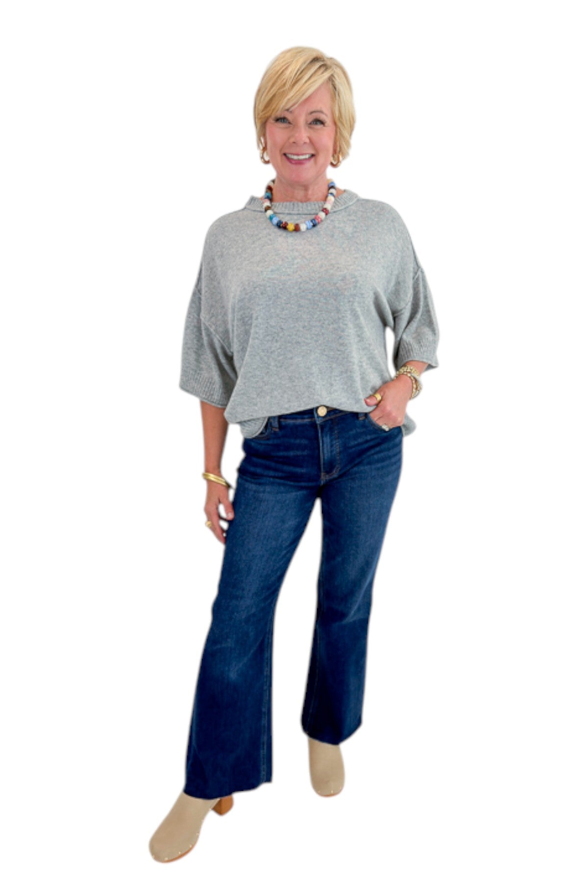 Front view of woman wearing Swagger Boutique’s Grey Short Sleeve Sweater with jeans against white studio background.