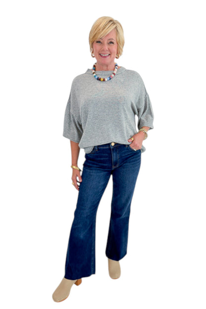 Front view of woman wearing Swagger Boutique’s Grey Short Sleeve Sweater with jeans against white studio background.
