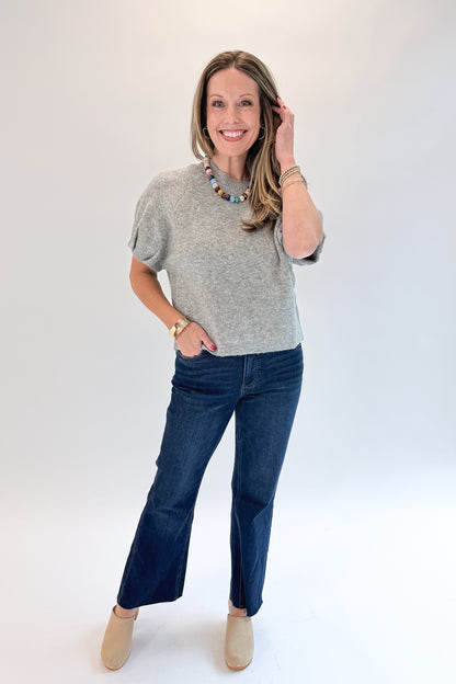 Front view of woman wearing Swagger Boutique’s Grey Short Sleeve Sweater with jeans against white studio background.