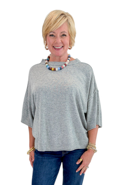 Front view of woman wearing Swagger Boutique’s Grey Short Sleeve Sweater with jeans against white studio background.
