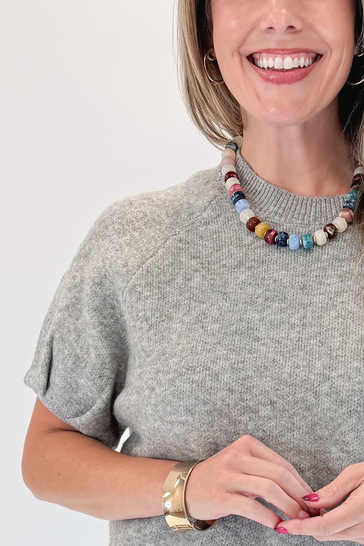 Front detail view of woman wearing Swagger Boutique’s Grey Short Sleeve Sweater with jeans against white studio background.