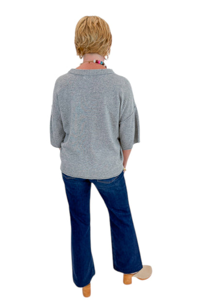 Back view of woman wearing Swagger Boutique’s Grey Short Sleeve Sweater with jeans against white studio background.