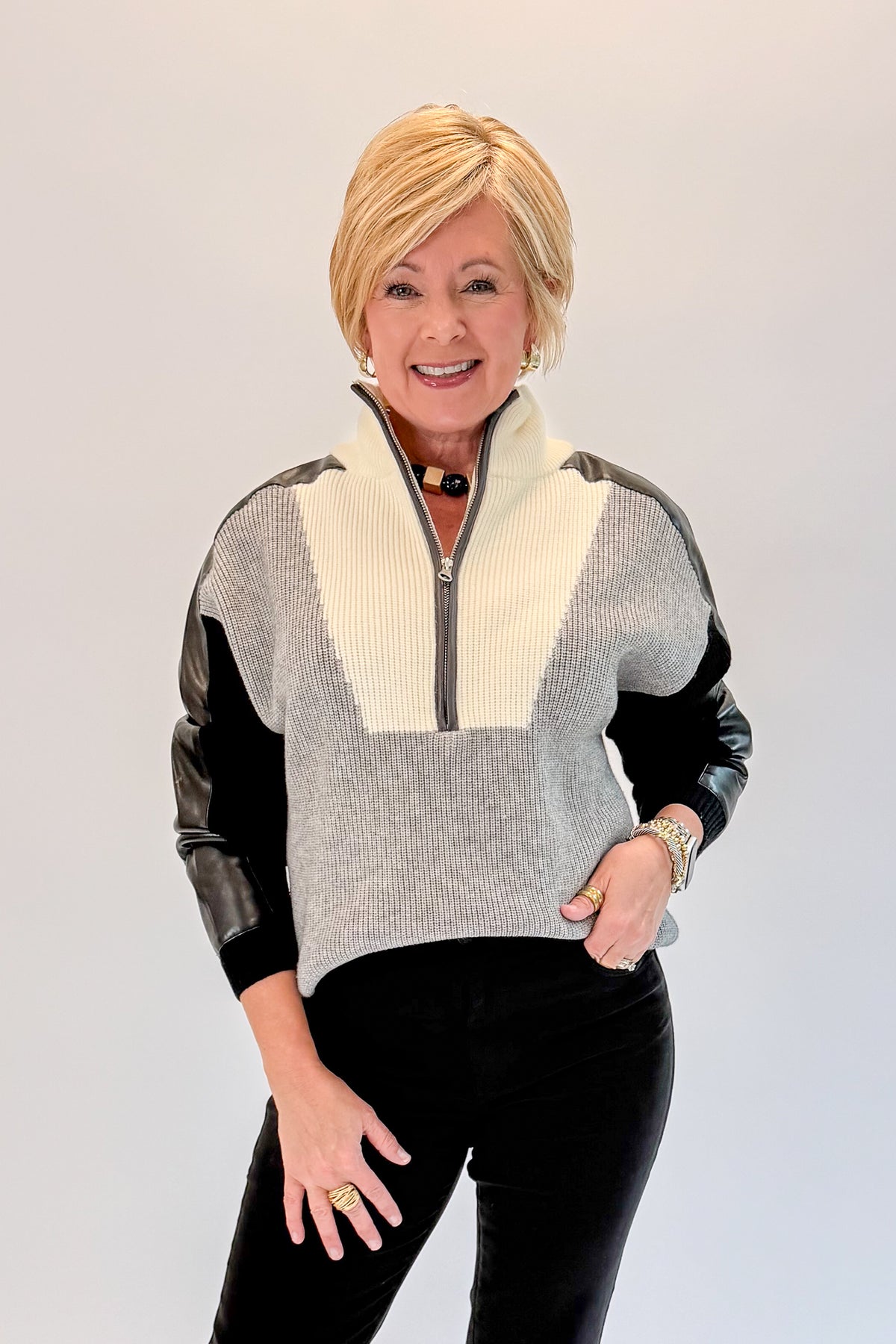 Front view of woman wearing Swagger Boutique’s Grey &amp; Black Color Block 1/4 Zip Sweater with jeans against white studio background.