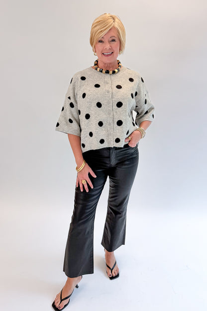 Front view of woman wearing Swagger Boutique’s Grey &amp; Black Polka Dot Short Sleeve Cardigan with jeans against white studio background.