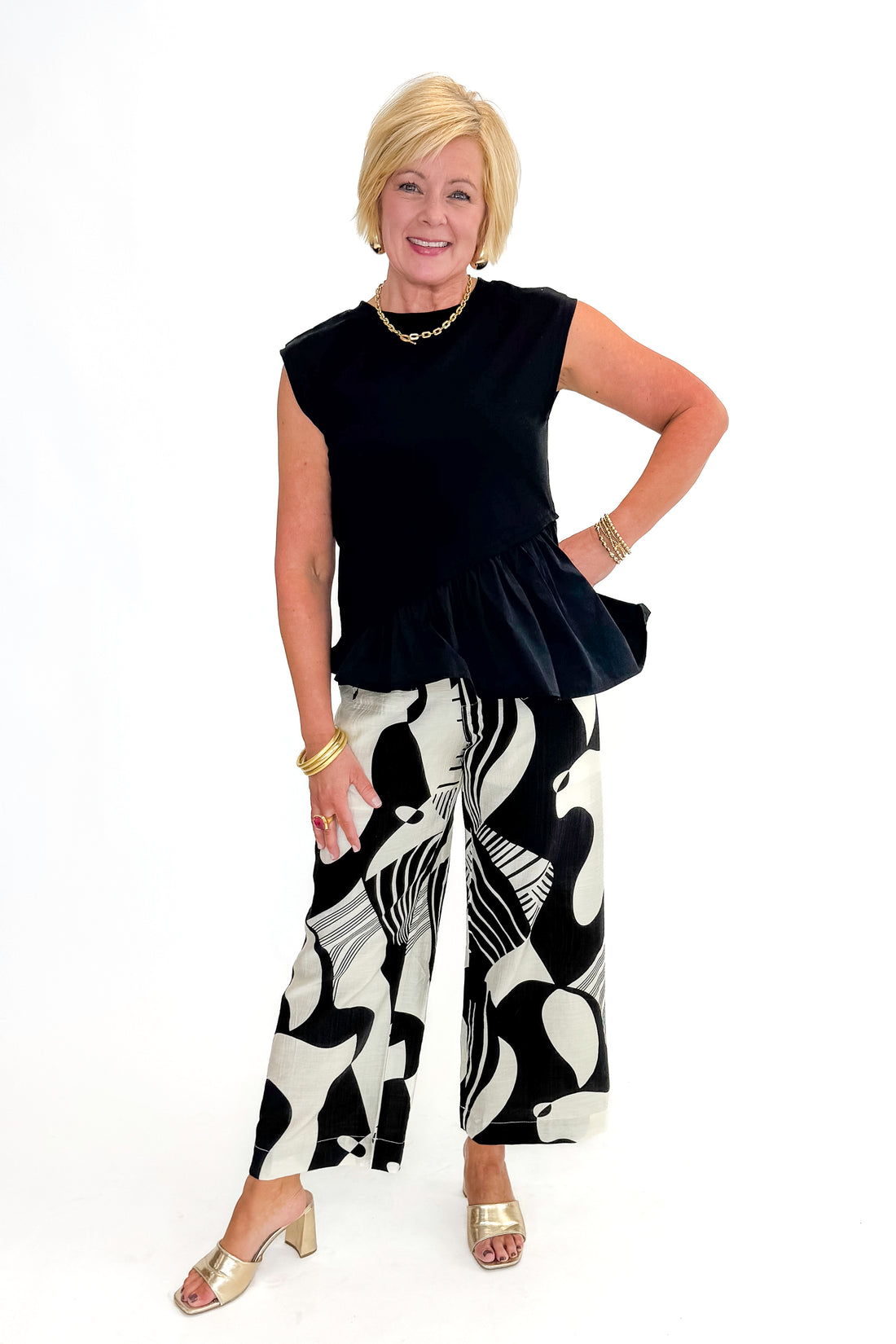 Front view of woman wearing Black Printed Pants with black top against white studio background.
