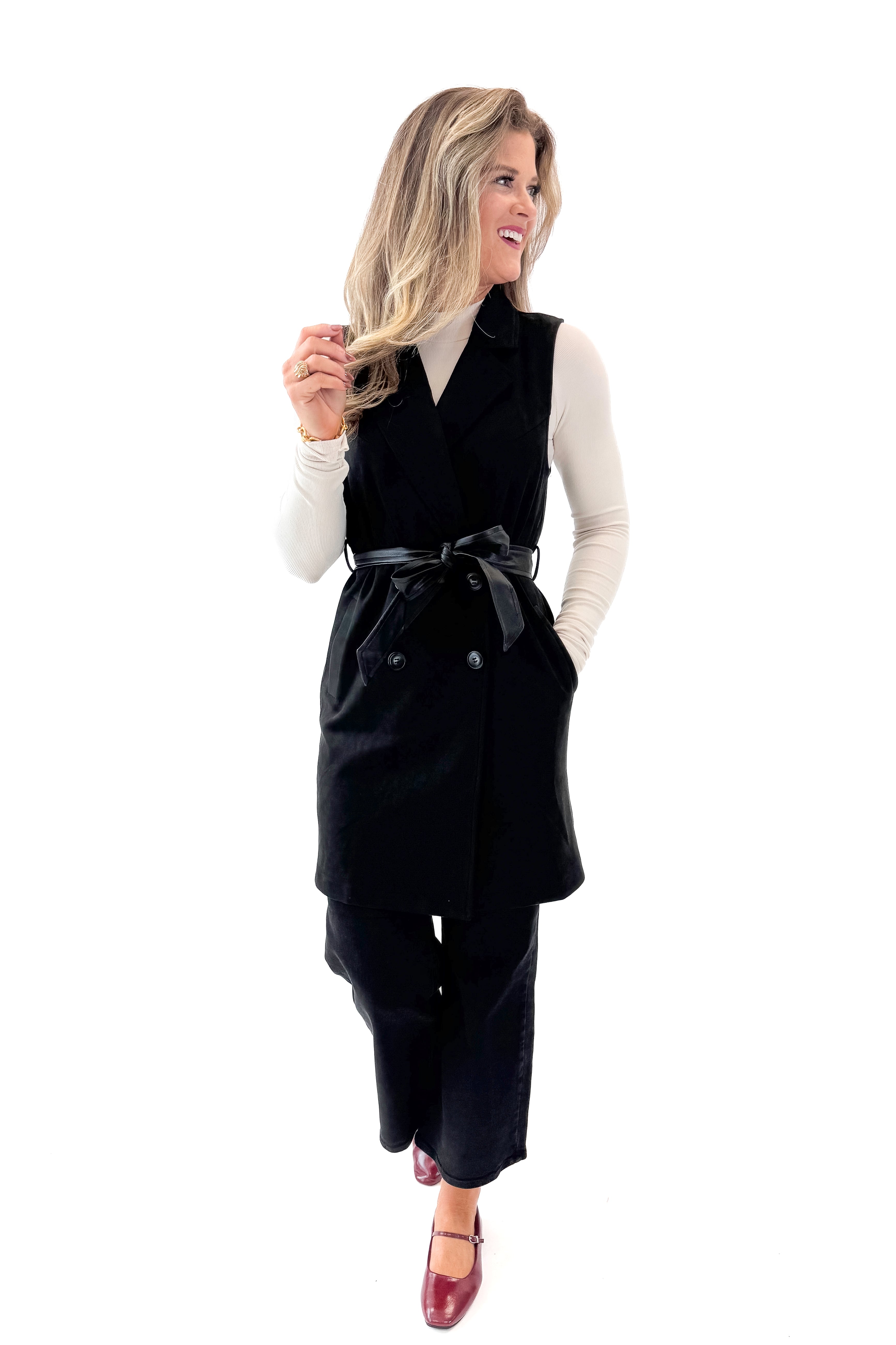 Front view of woman wearing Black Suede Long Vest with jeans against white studio background.