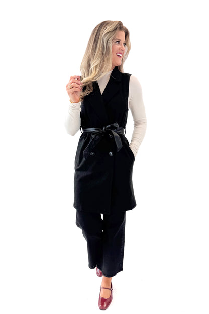 Front view of woman wearing Black Suede Long Vest with jeans against white studio background.