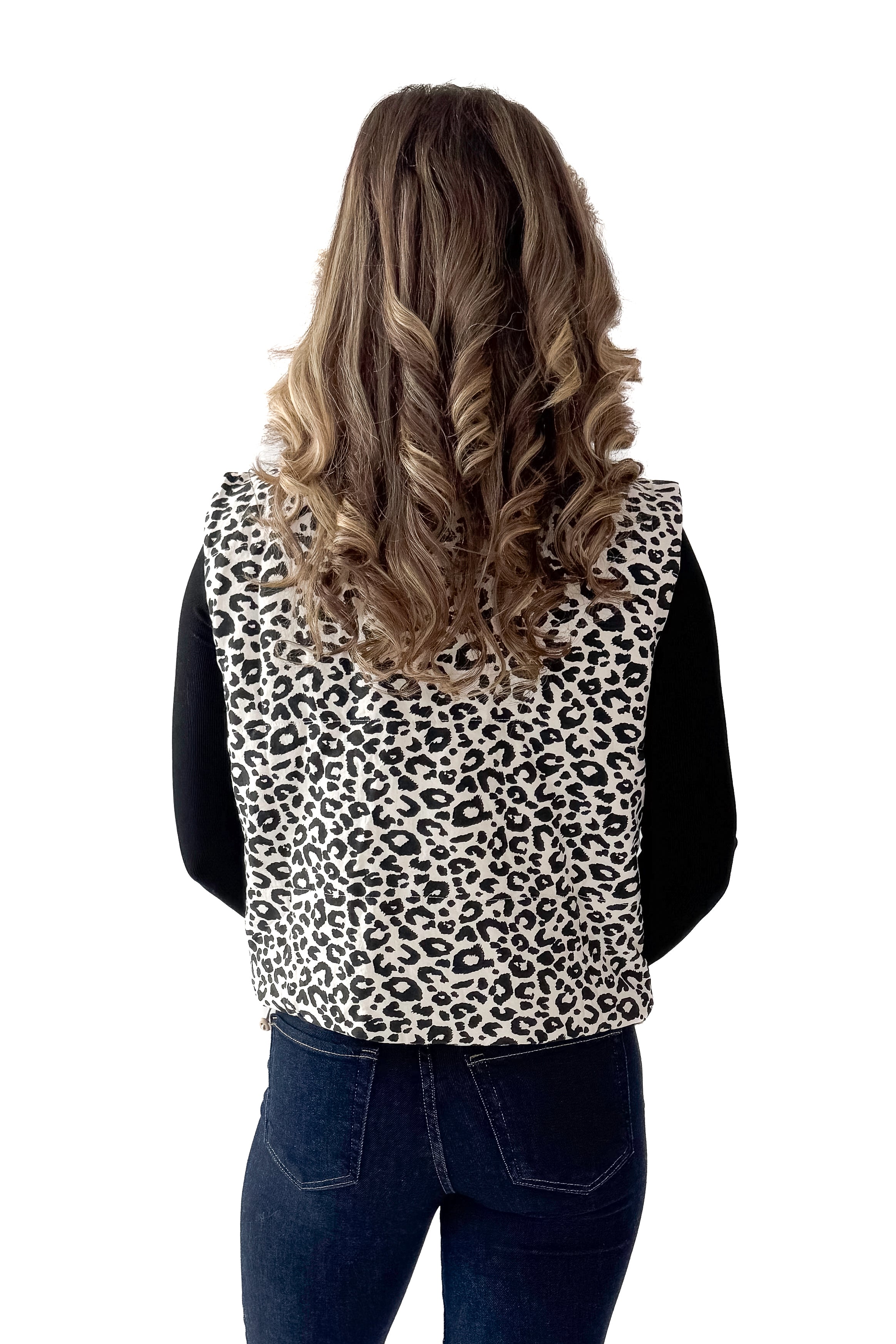 Back view of woman wearing Cream Leopard Puffer Vest with jeans against white studio background.