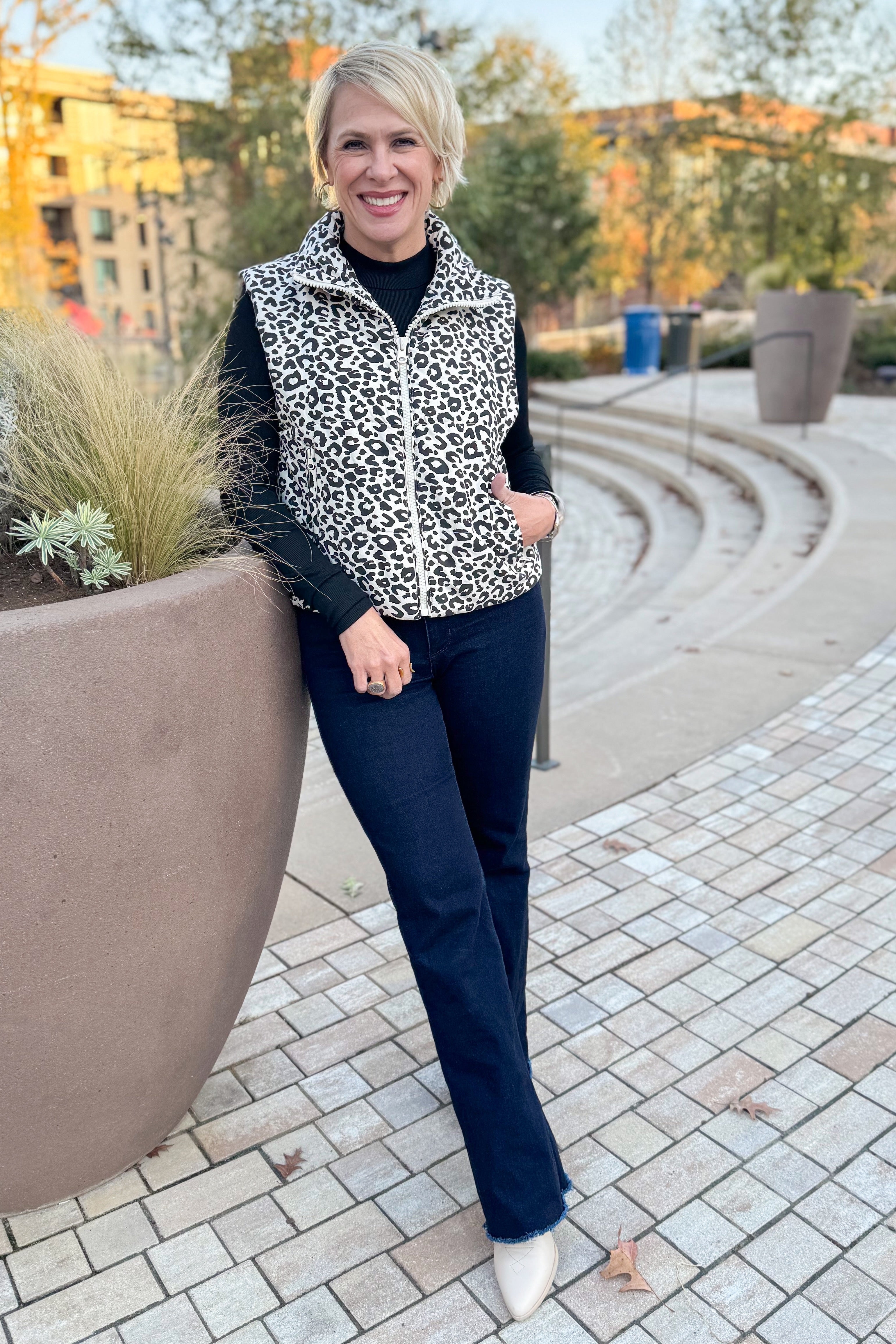 Front view of woman wearing Cream Leopard Puffer Vest with jeans outside.