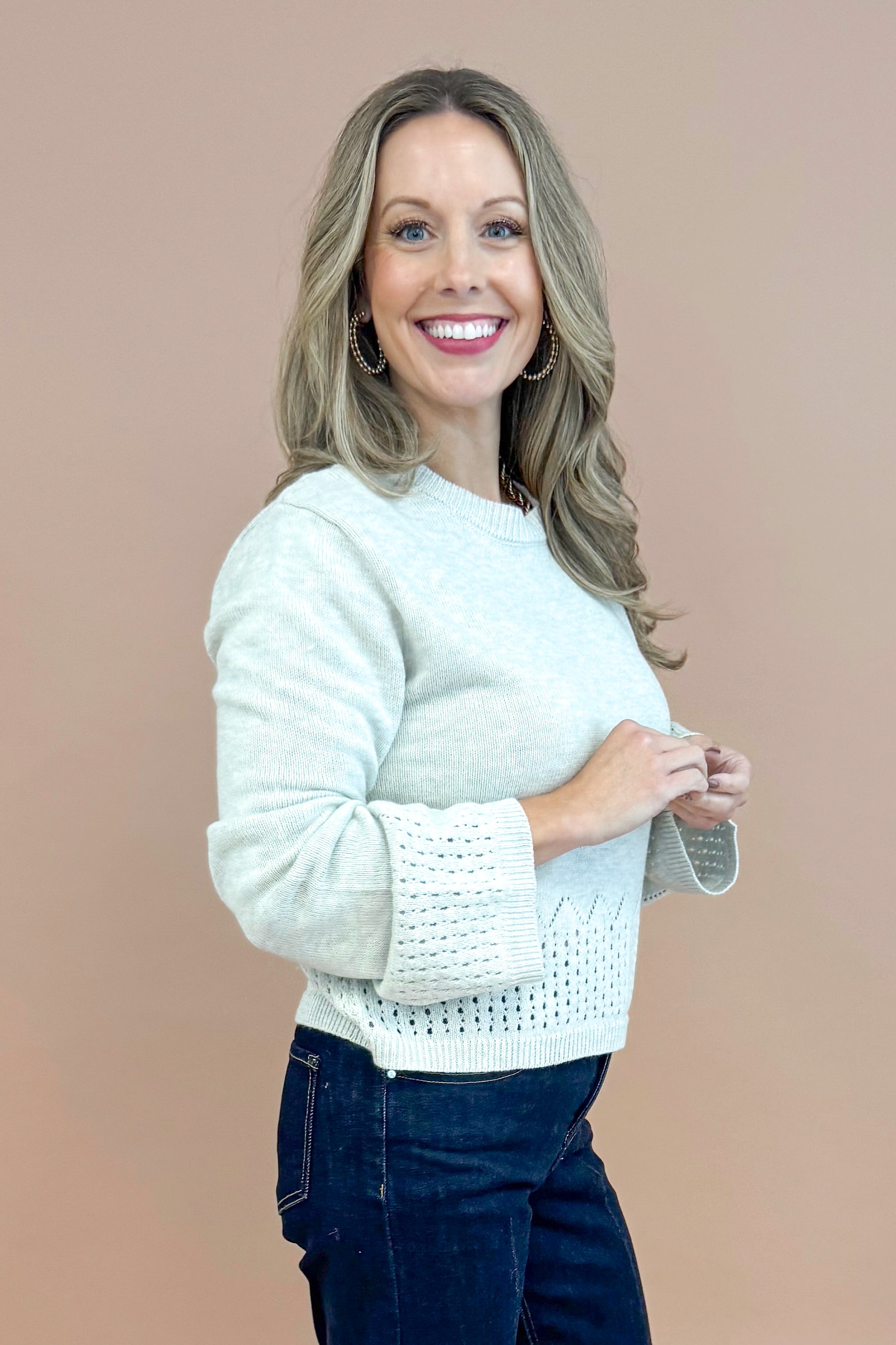 Side view of woman wearing Grey Cutout Detail Sweater and blue jeans. 