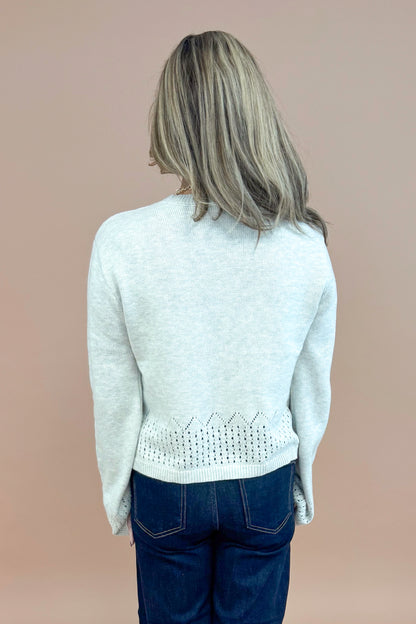Back view of woman wearing Grey Cutout Detail Sweater and blue jeans. 
