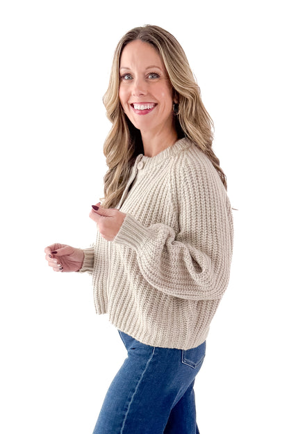 Side view of woman wearing Light Mocha Button Up Cardigan with jeans against white studio background.