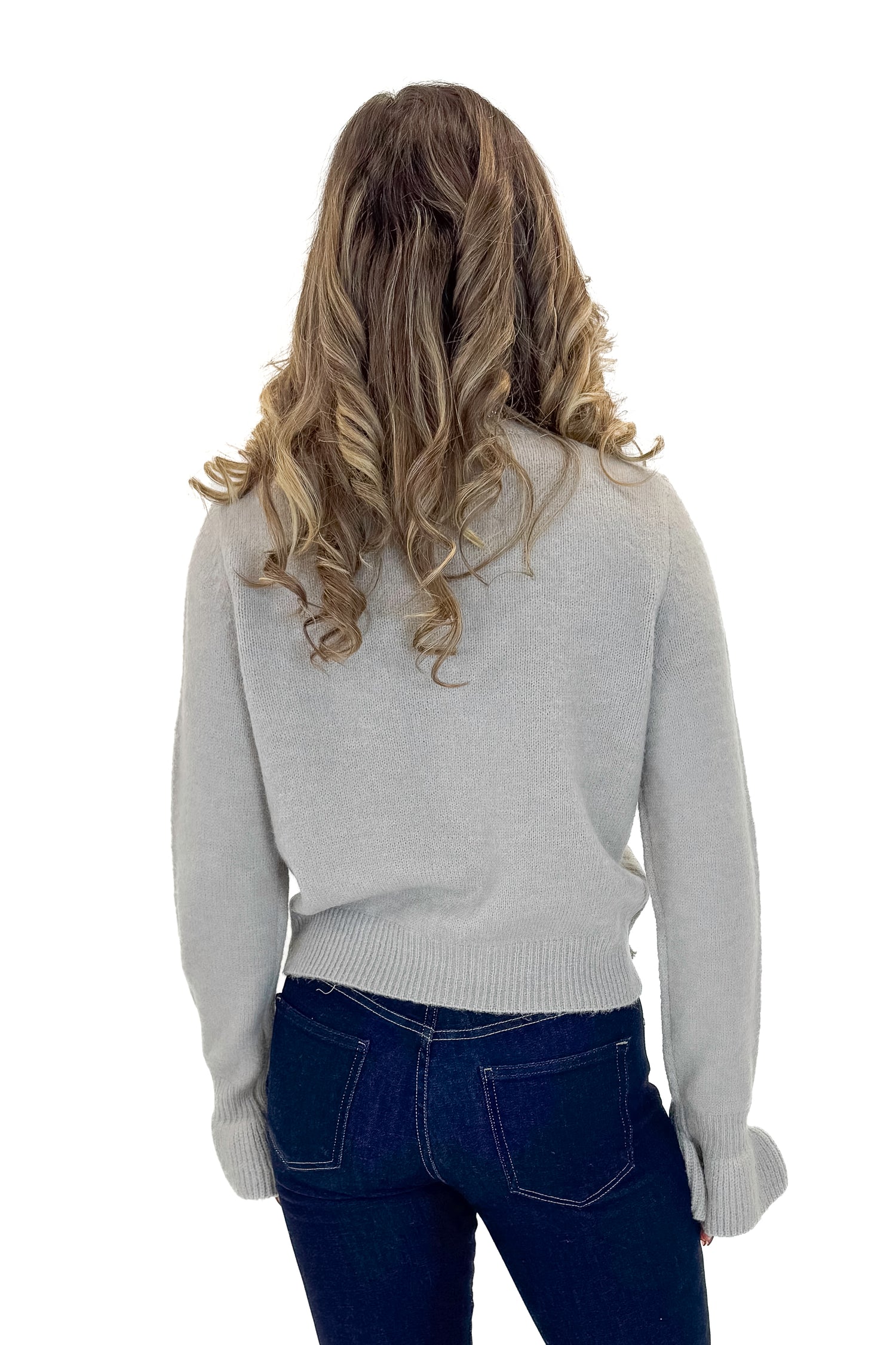 Back view of woman wearing Grey Button Up Bow Detail Sweater with jeans against white studio background.