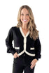Front view of woman wearing Black & White Contrast Trim Cardigan with jeans against white studio background.