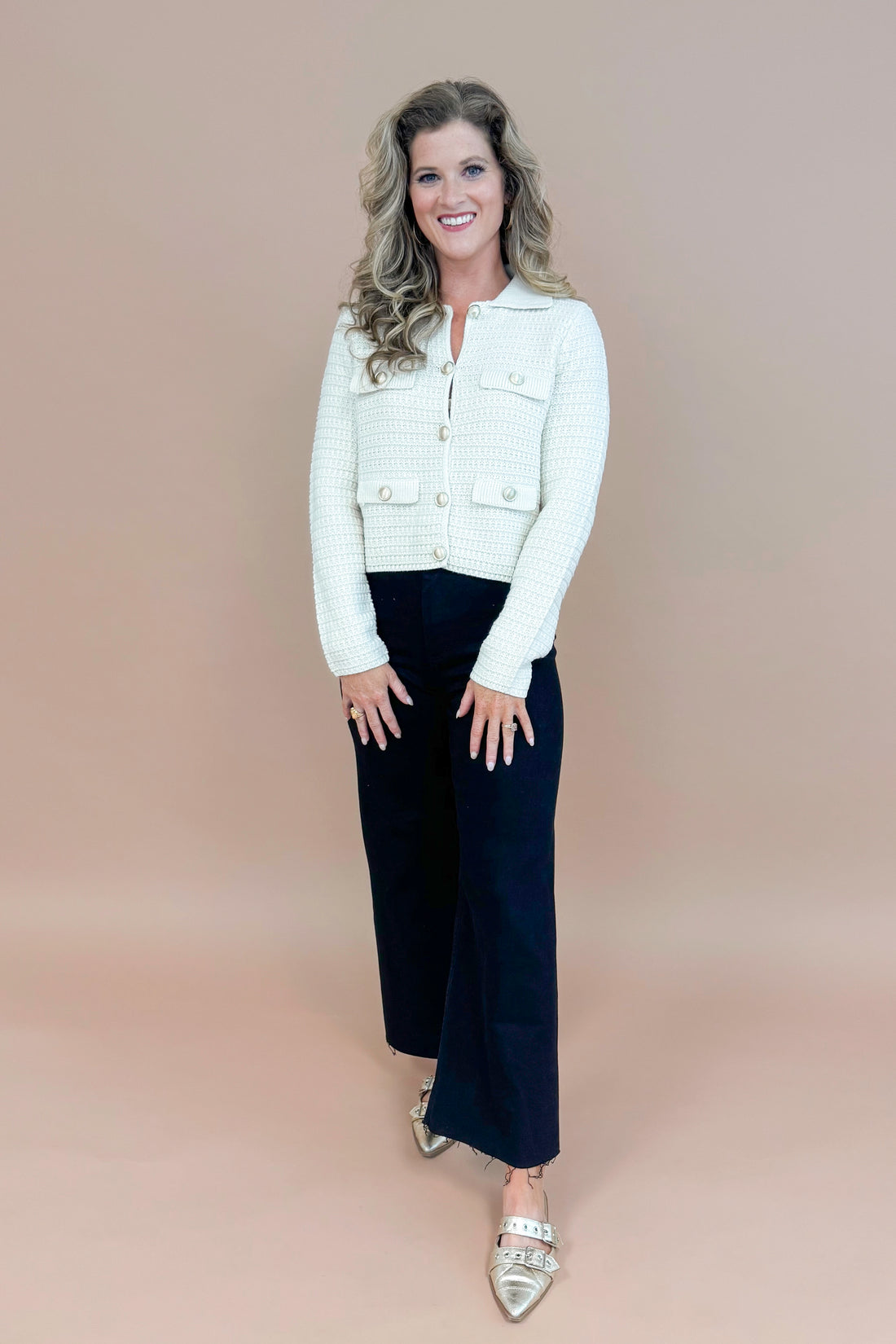 Picture of woman wearing Cream Textured Button Up Cardigan and jeans with taupe background.