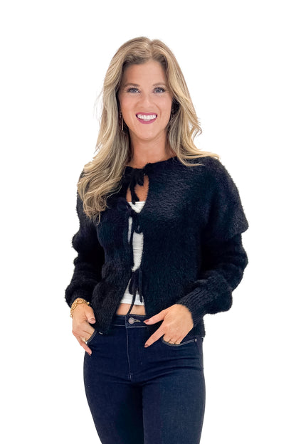 Front view of woman wearing Black Eyelash Tie Detail Cardigan with jeans against white studio background.
