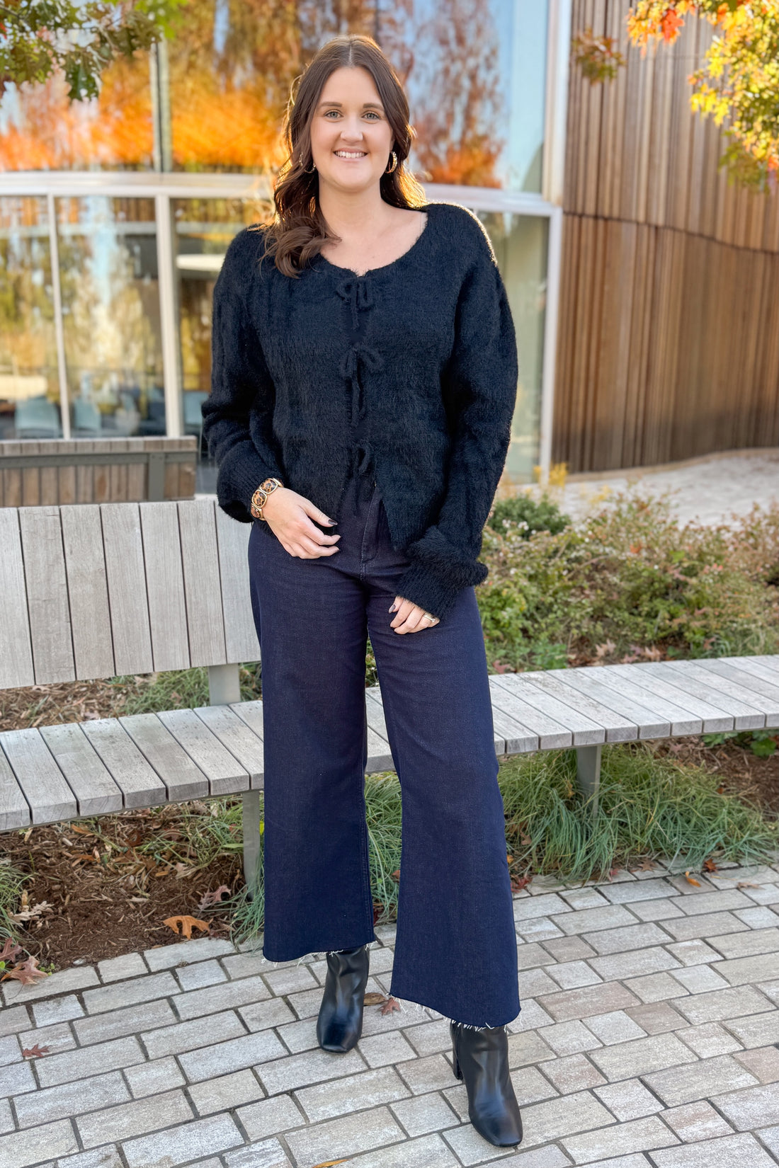 Front view of woman wearing Black Eyelash Tie Detail Cardigan with jeans outside.