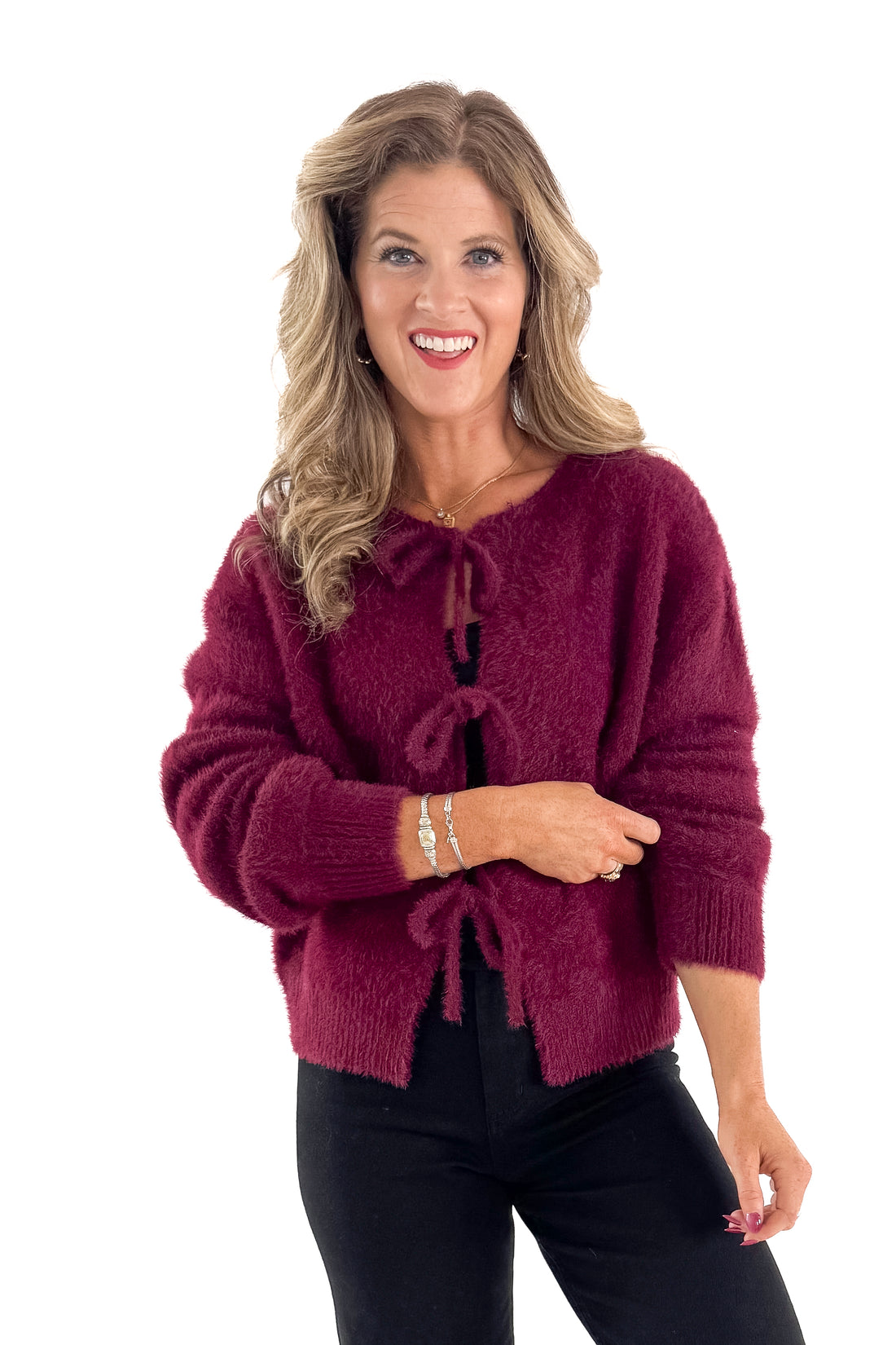 Front view of woman wearing Wine Eyelash Tie Detail Cardigan with jeans against white studio background.