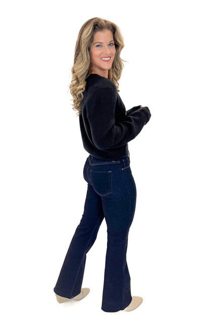 Side view of woman wearing Black Cardigan With Rhinestone Bow with jeans against white studio background.