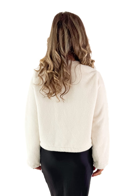 Back view of woman wearing Cream Faux Fur Toggle Button Jacket with black skirt against white studio background.