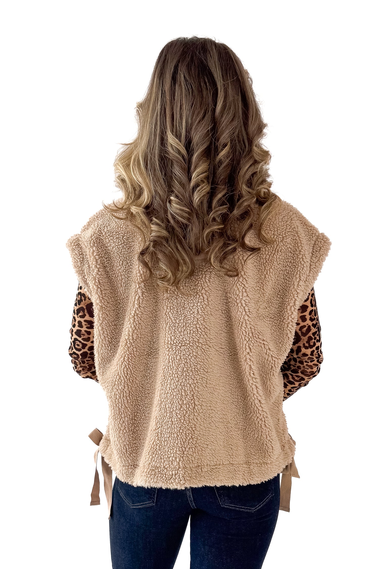 Back view of woman wearing Taupe Sherpa Button Up Vest with jeans against white studio background.