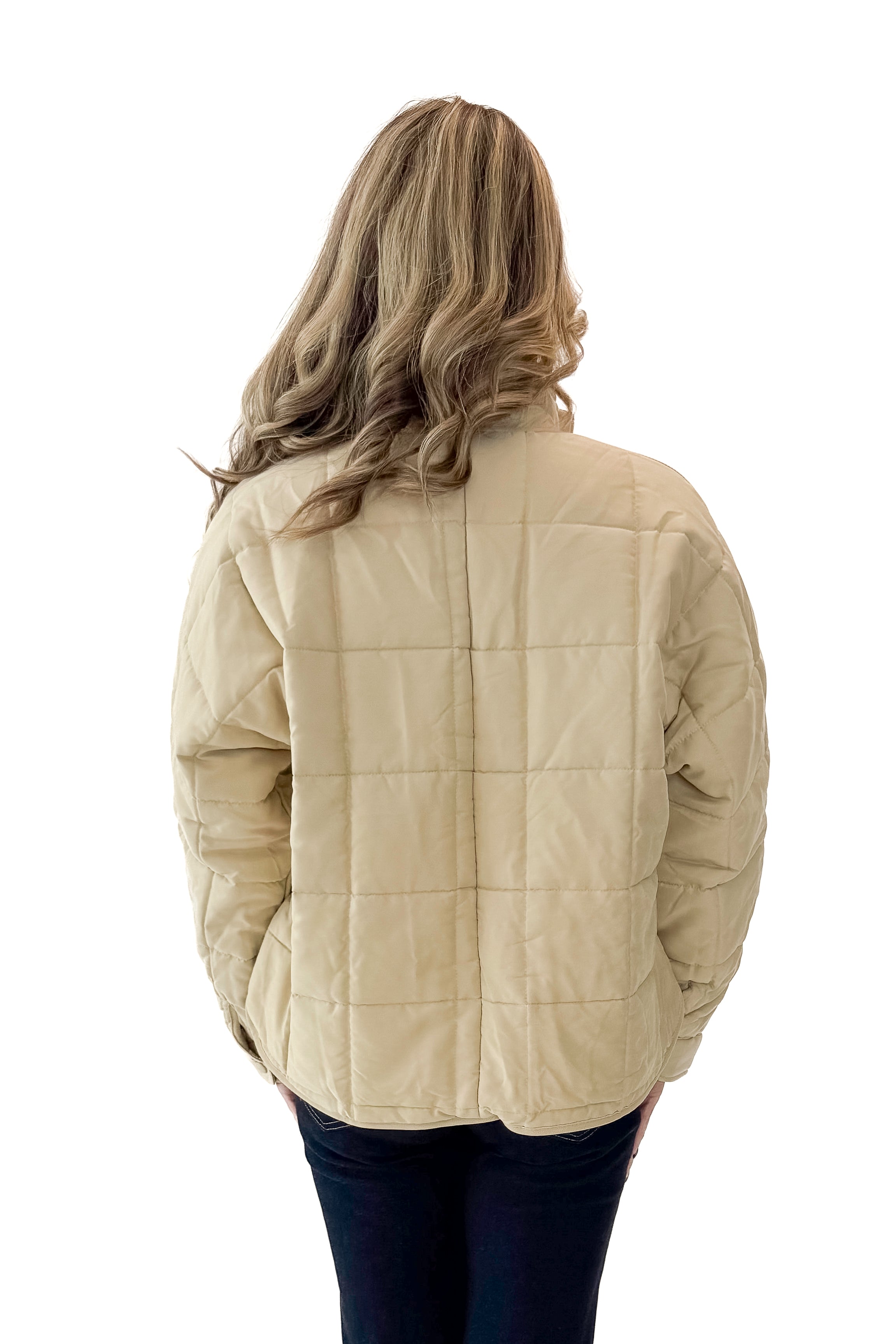 Back view of woman wearing Beige Quilted Puffer Jacket with jeans against white studio background.