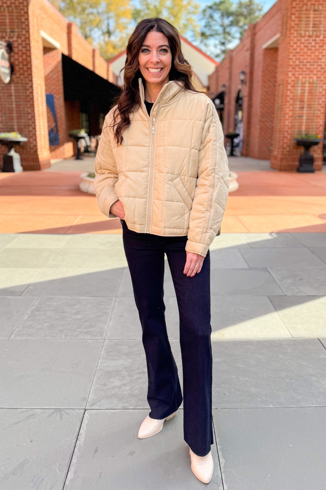 Front view of woman wearing Beige Quilted Puffer Jacket with jeans outside.