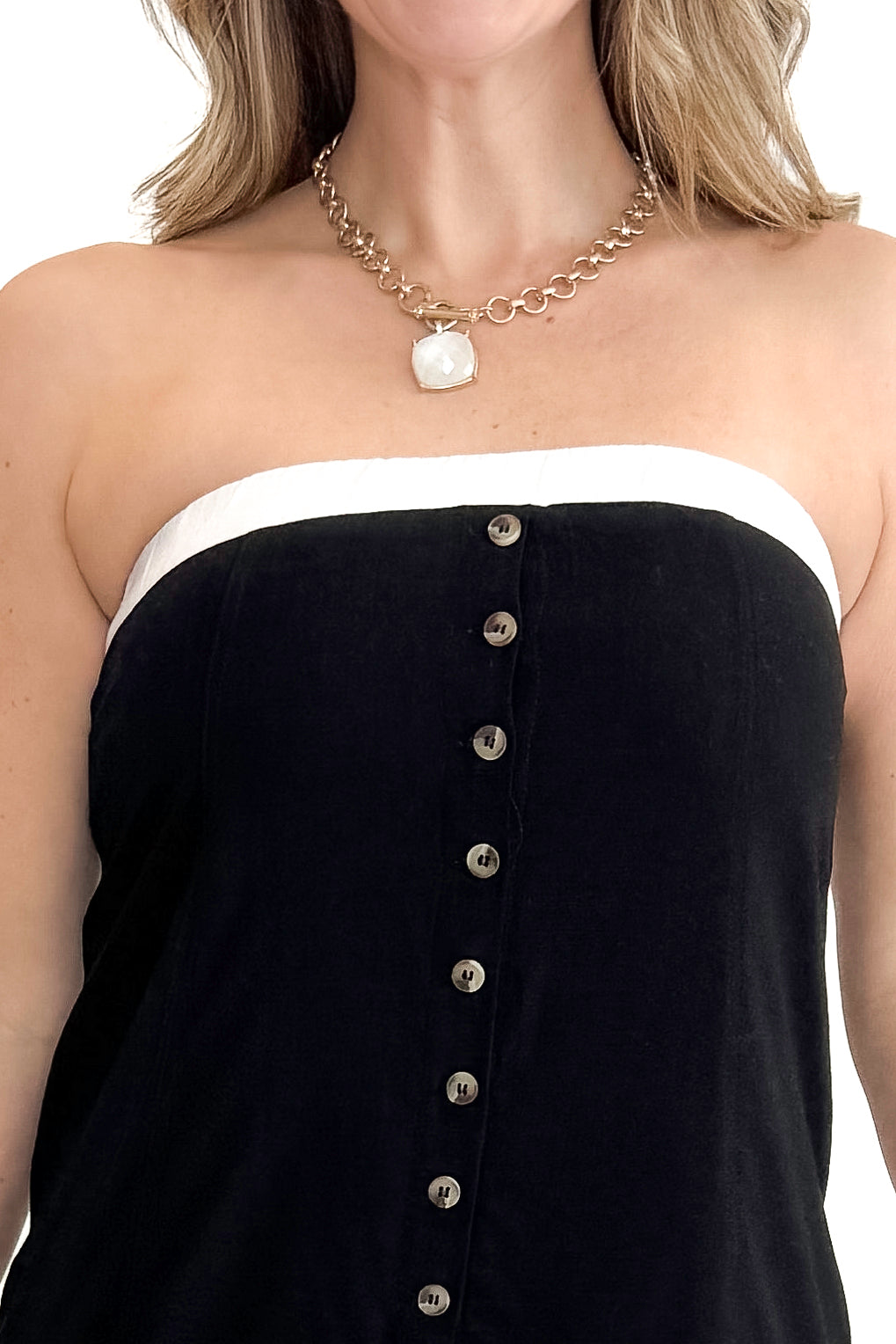 Front detail view of woman wearing Black With White Lining Button Down Strapless Dress against white studio background.