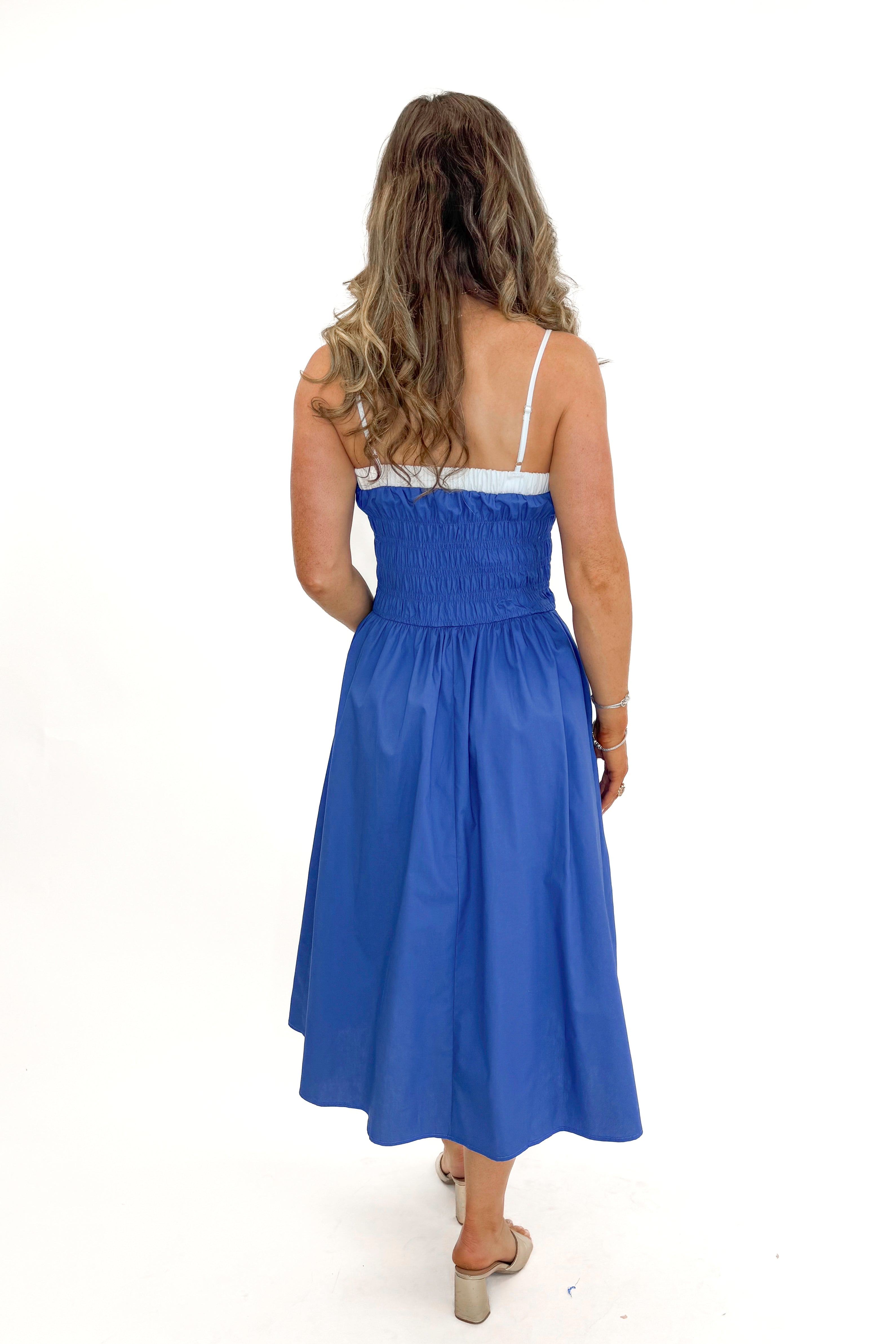 Back view of woman wearing Blue With White Color Block Smocked Midi Dress against white studio background.