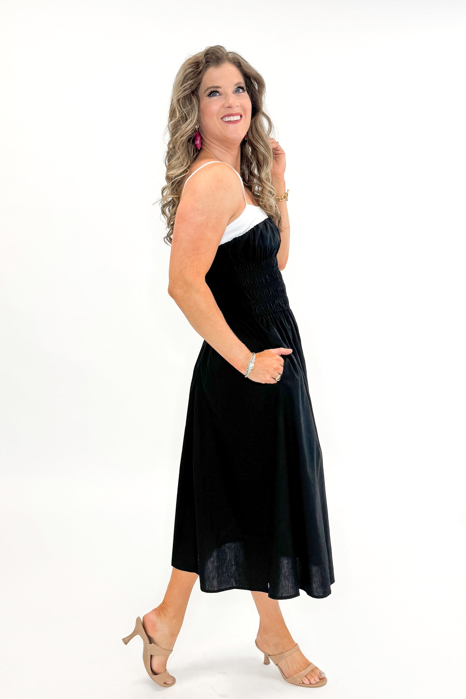 Side view of woman wearing Black With White Color Block Smocked Midi Dress against white studio background.